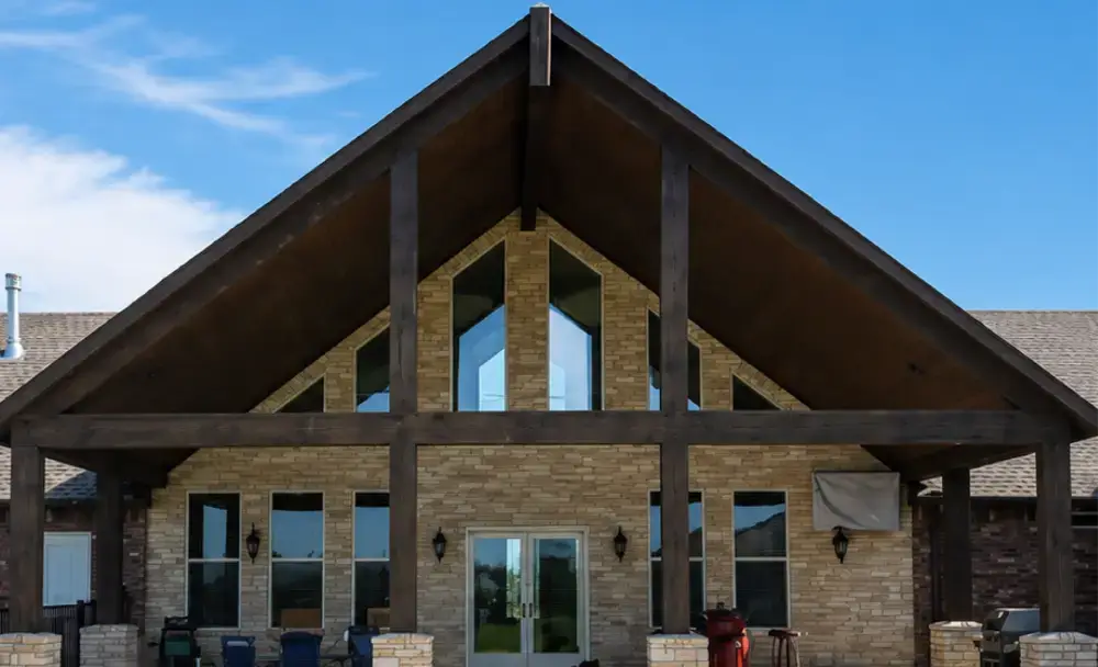 Custom home covered patio with vaulted wood ceiling and stone columns