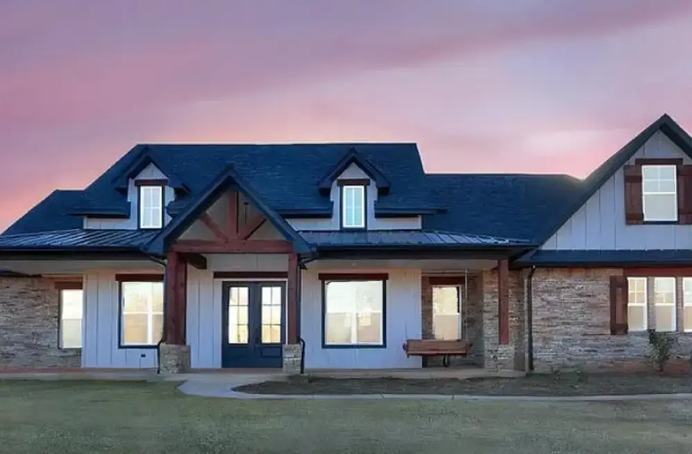 Custom farmhouse-style home exterior at dusk with stone accents and covered porch